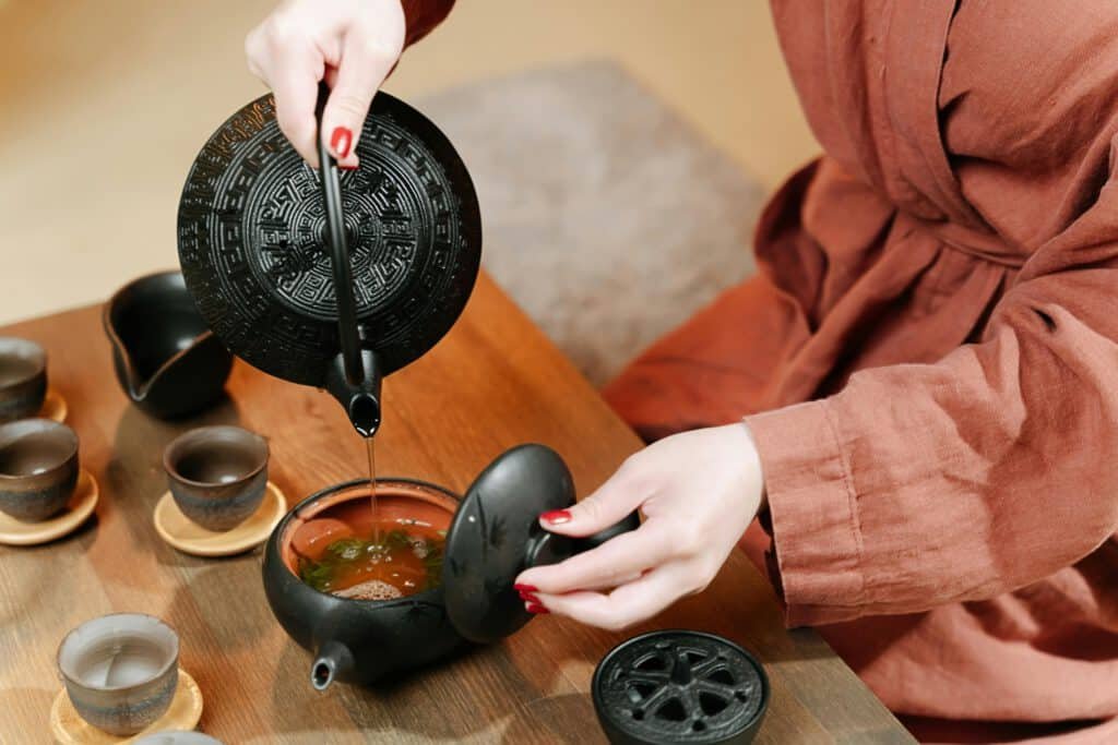 Close-up of a traditional tea ceremony featuring black teaware and a person pouring tea.