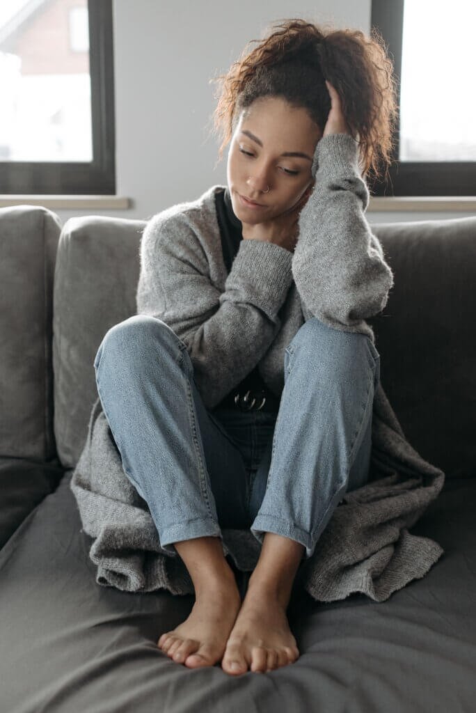 Woman sitting on her sofa at home, thoughtful and relaxed